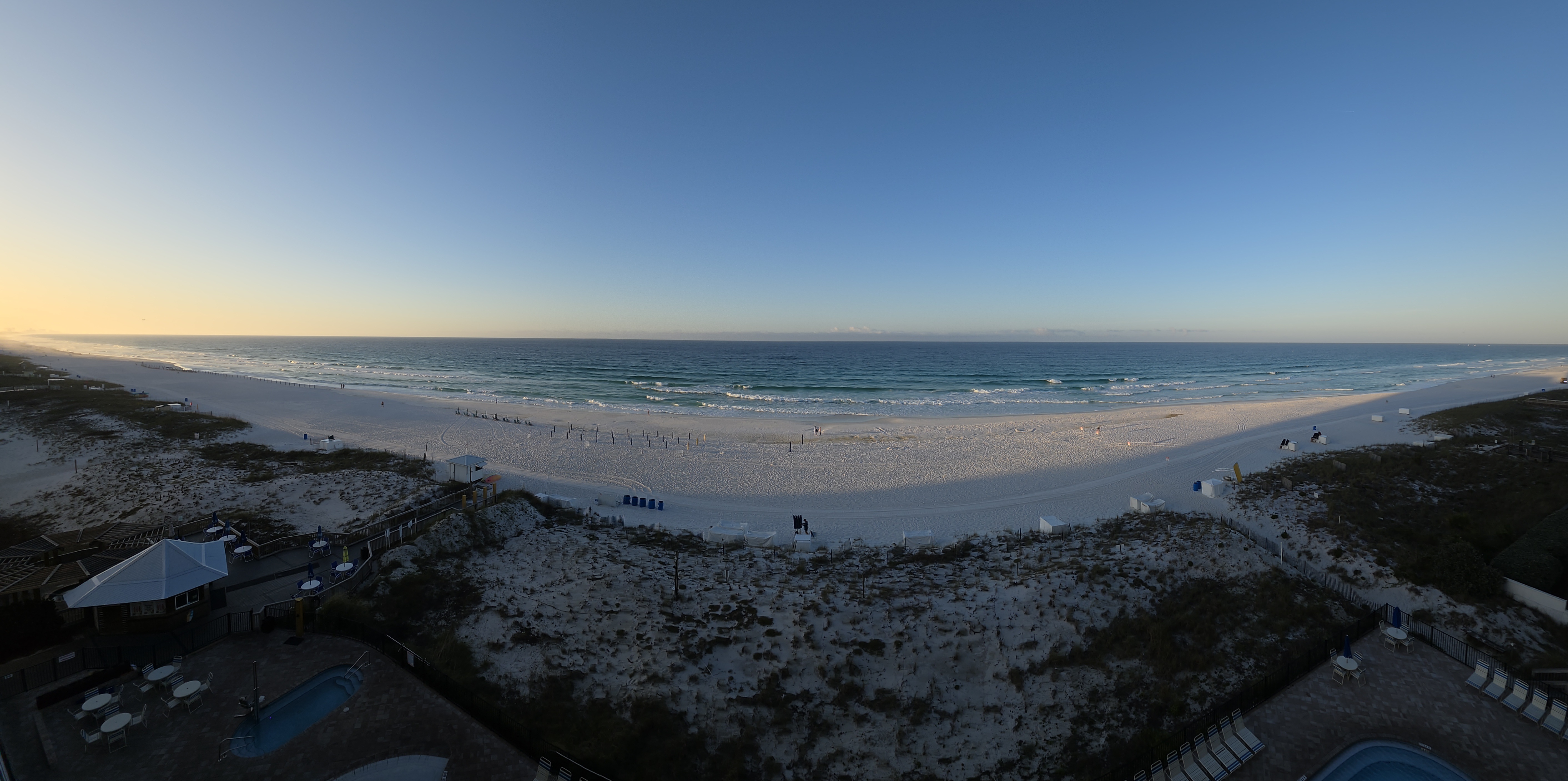 Wide morning view of the beach and pools from Pelican Beach Resort